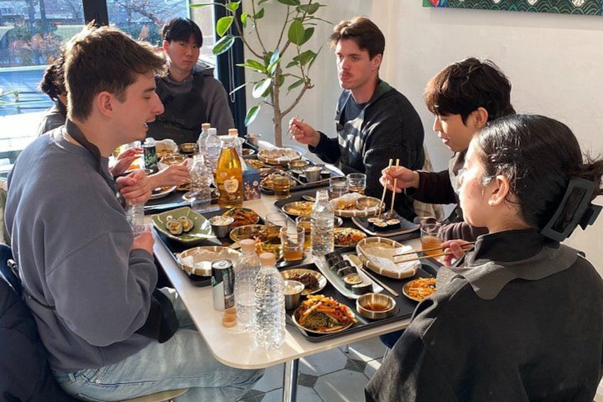 Een groep mensen dineert aan tafel met diverse gerechten en drankjes. 1
