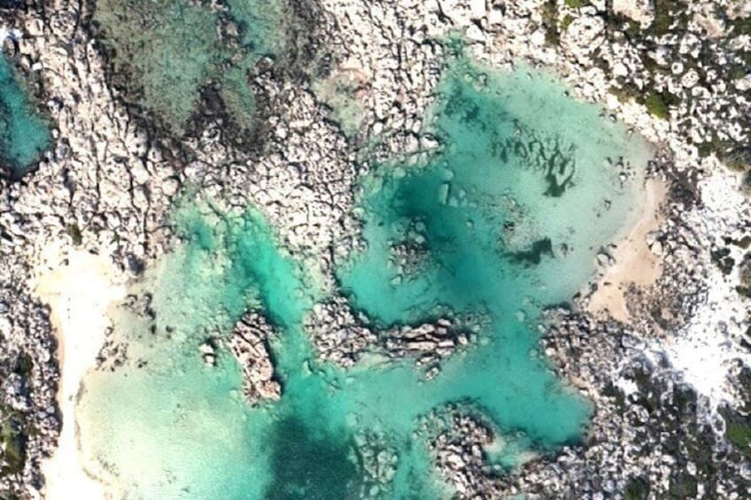 Un paisaje costero con aguas turquesas cristalinas, afloramientos rocosos y playas arenosas. 2