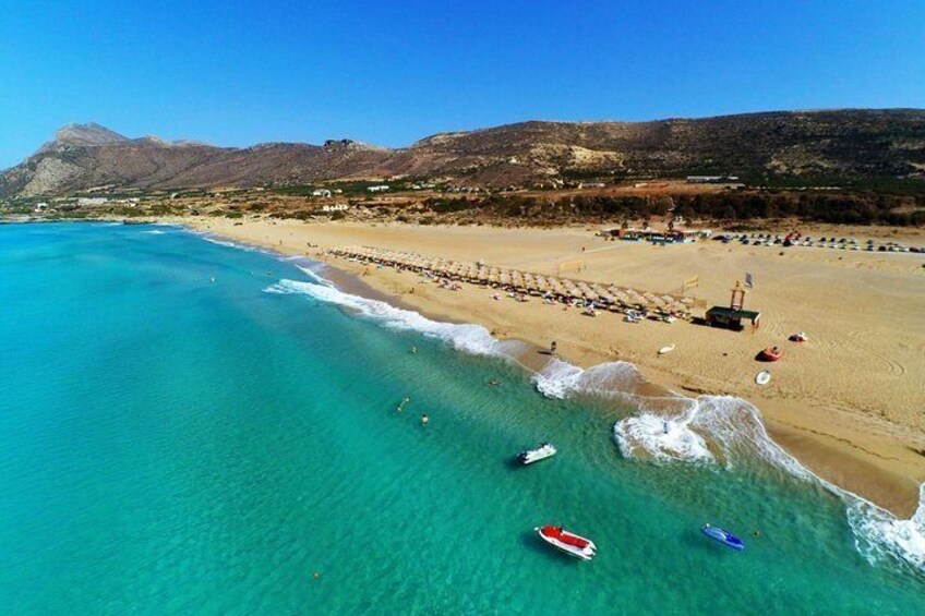 Una playa con agua turquesa cristalina, una orilla arenosa y barcos. 1