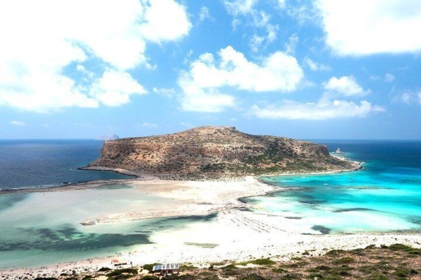 Un paisaje costero con una isla rocosa destacada, aguas turquesas cristalinas y una playa de arena. 3