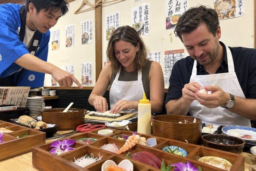 Three people preparing food at a wooden table with various dishes and ingredients. 1