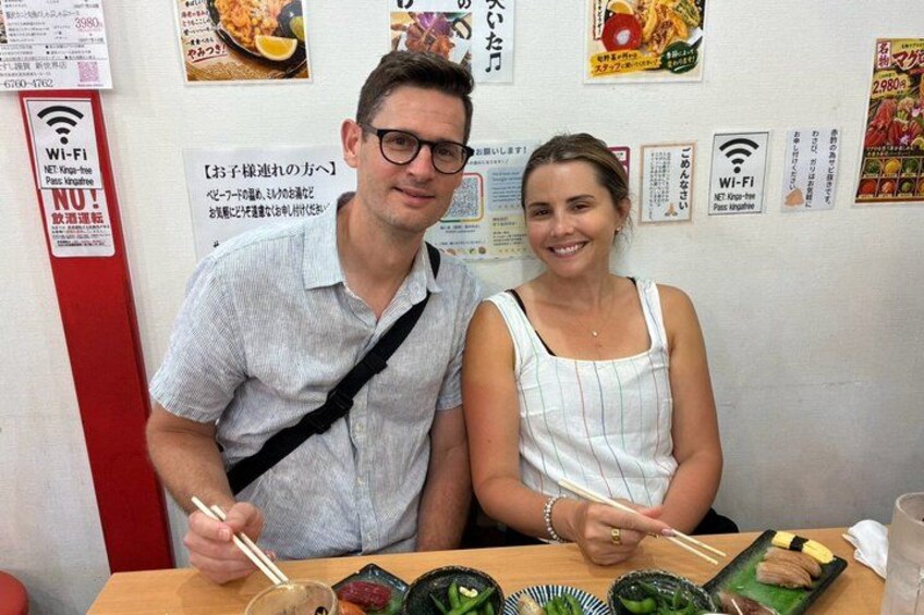 A man and a woman sitting at a table with chopsticks, eating sushi. 3