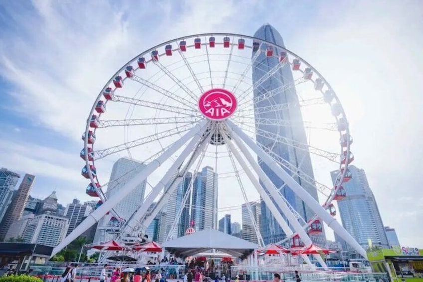 A large Ferris wheel with a red center, surrounded by skyscrapers. 2