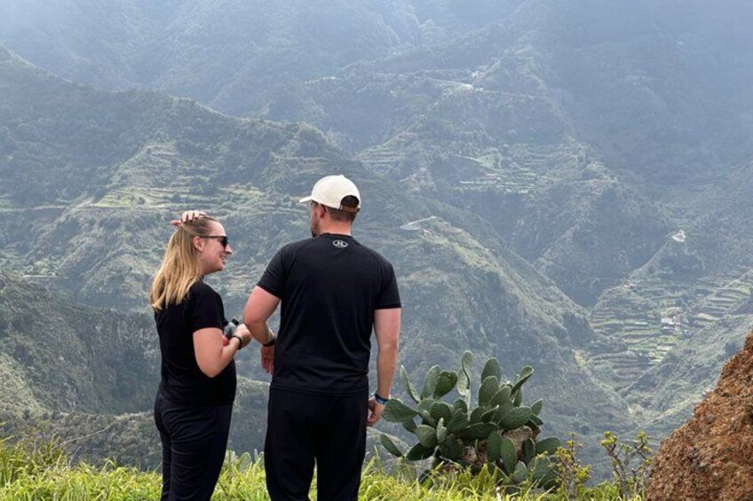Two people standing on a hill overlooking a mountainous landscape. 3
