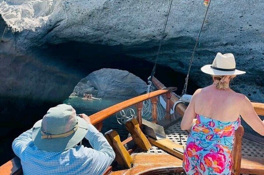 A boat with two people, one in a hat and the other in a colorful dress, overlooking a cave entrance. 3