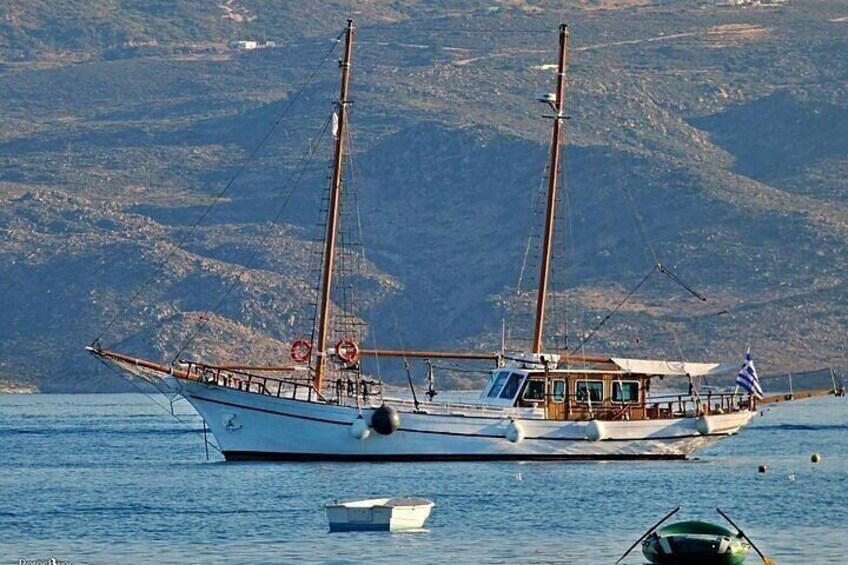A sailboat with two masts, anchored in calm waters with a mountainous landscape in the background. 1