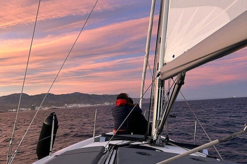 Una persona su una barca a vela con una costa montuosa sullo sfondo. 2