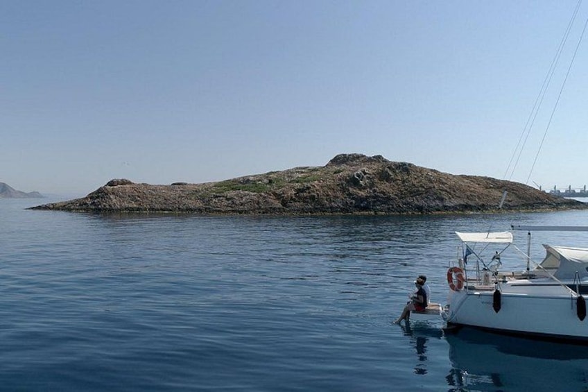 Un'acqua calma con una barca ancorata vicino a un'isola rocciosa. 2
