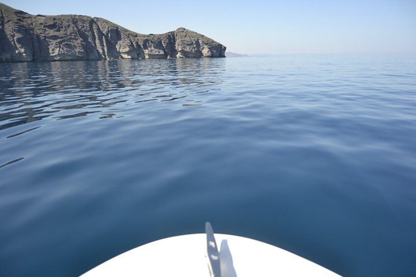 Calm sea water, a boat, and rocky cliffs. 2