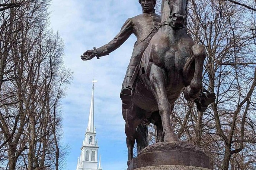 A statue of a man on horseback with a church spire in the background. 2