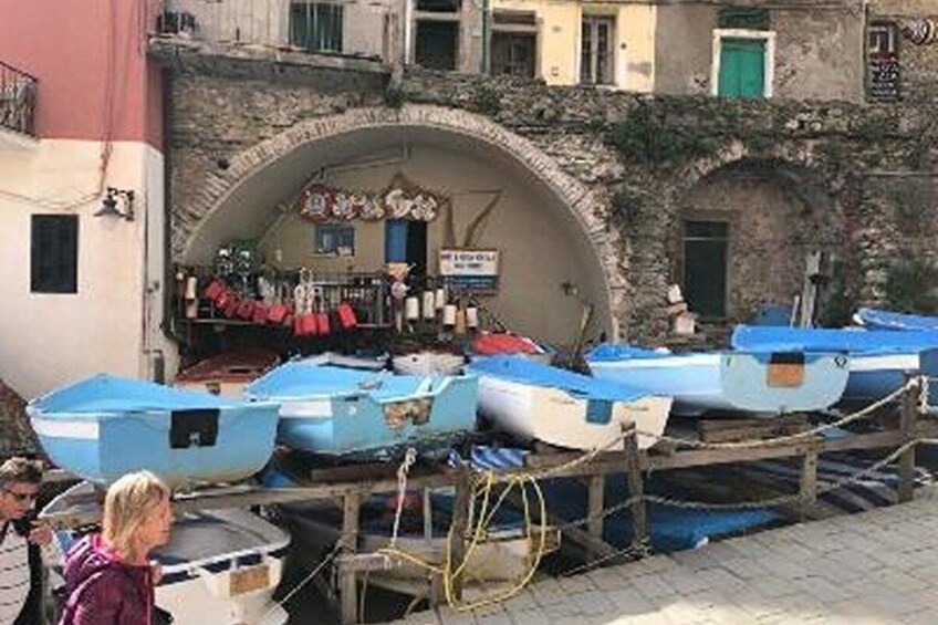 A row of small boats docked at a stone archway in a harbor. 4