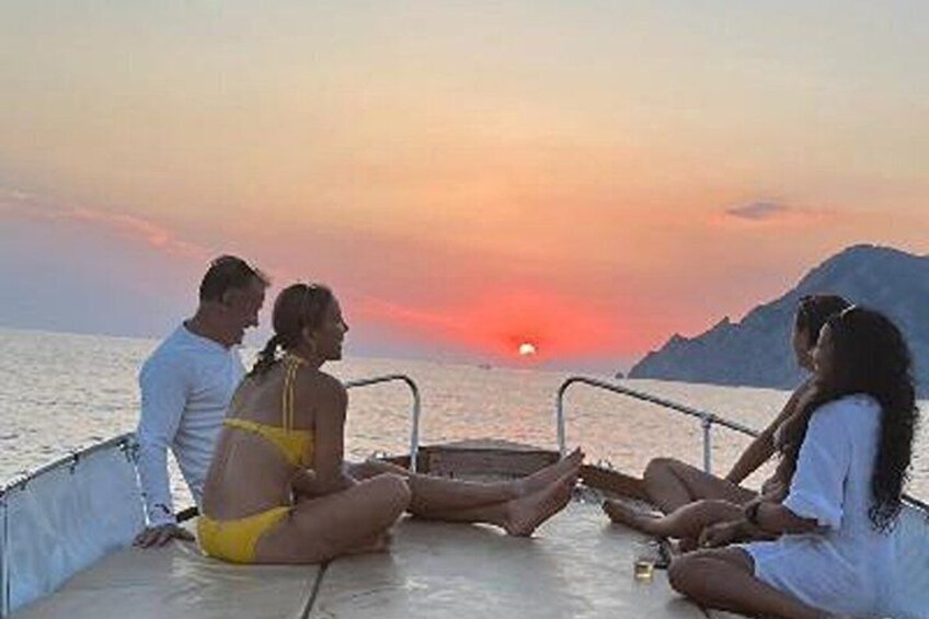 A sunset over the ocean with people sitting on a boat. 5