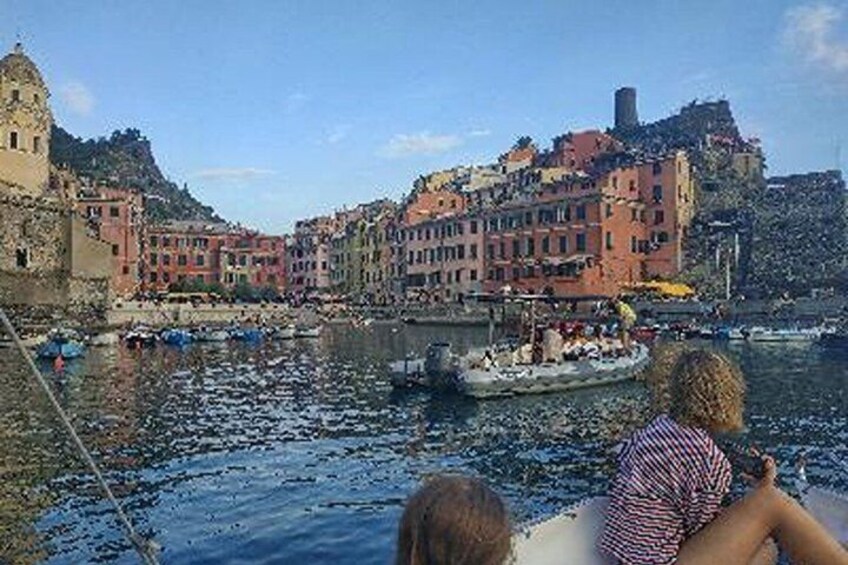 A coastal town with colorful buildings, a boat on the water, and a historic tower. 2