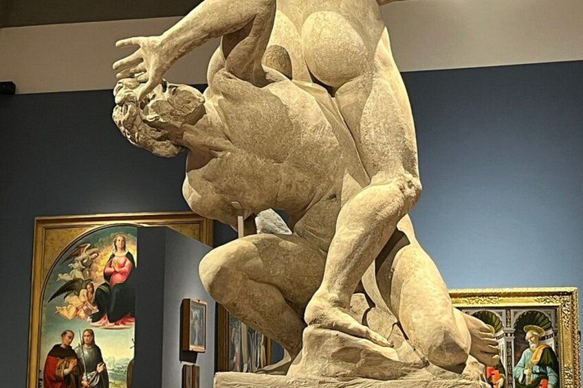 Una gran escultura de piedra de una figura arrodillada, un cuadro enmarco y una estatua de un santo. 2