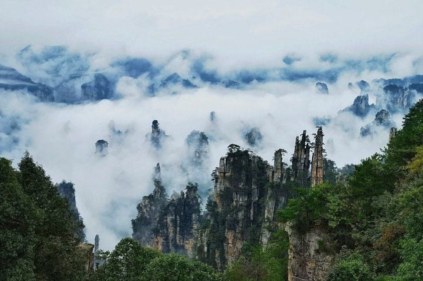 A mountainous landscape with towering rock formations and dense forest. 5