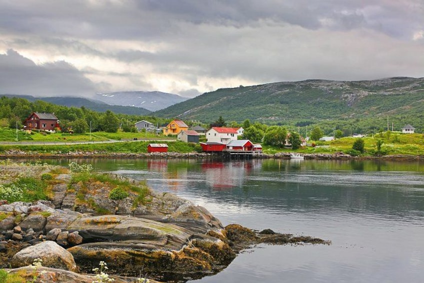 A calm lake with houses and mountains in the background. 2