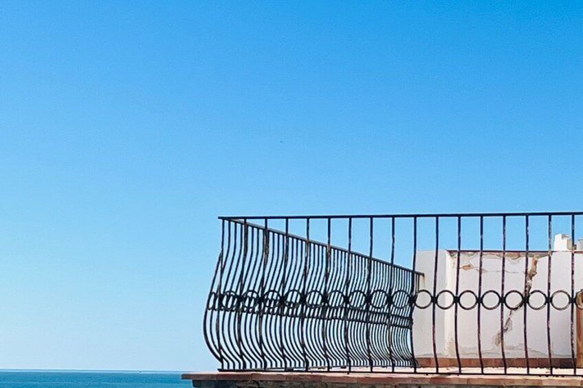 Une clôture en métal au design incurvé, un ciel bleu dégagé et une étendue d’eau en arrière-plan. 4