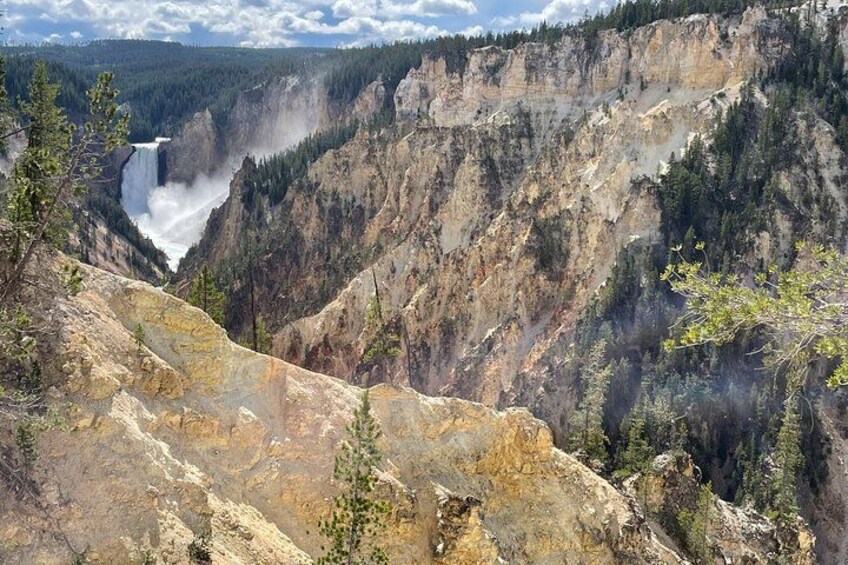 A canyon with a waterfall, rocky terrain, and sparse vegetation. 3