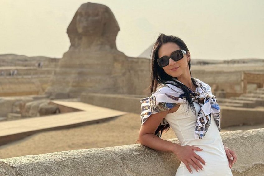 A person leaning on a stone structure with the Great Sphinx in the background. 1