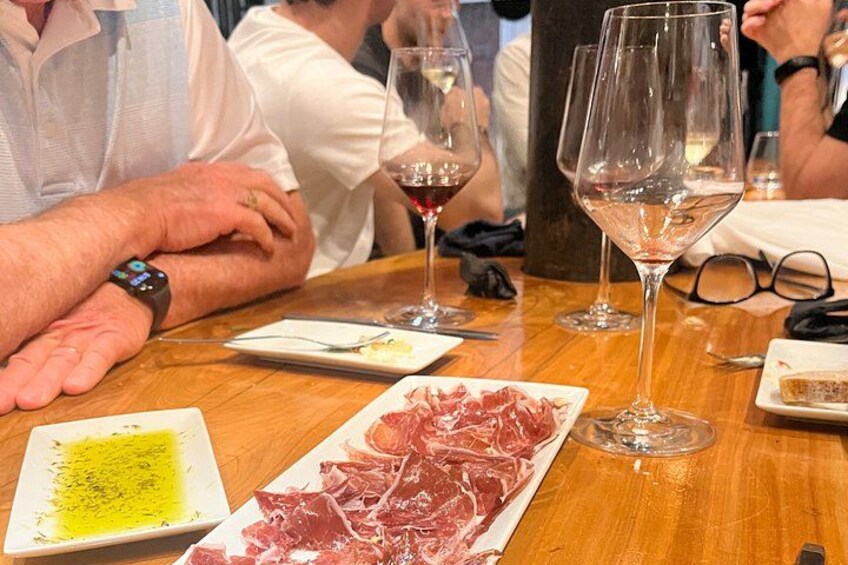 A wooden table with plates of food, wine glasses, and a bottle. 1