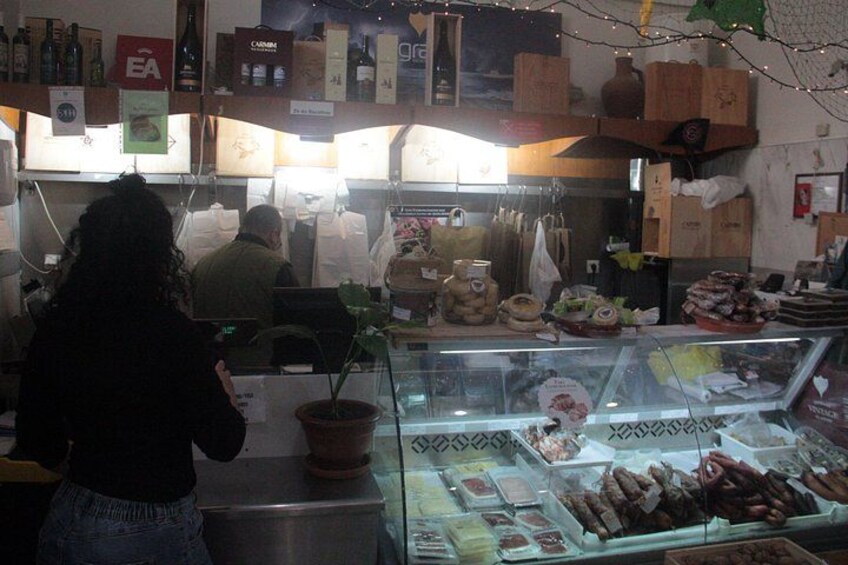 A deli counter with various food items and a customer. 4