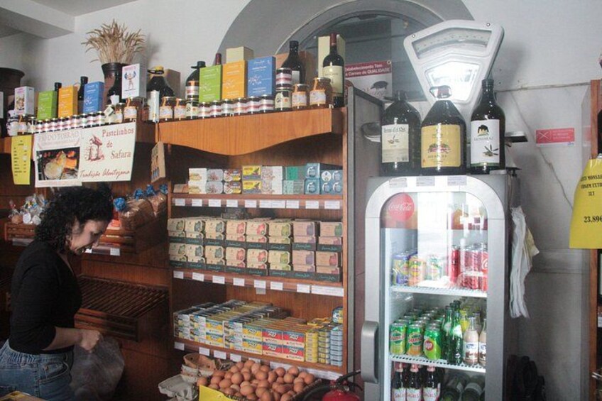 A store with shelves of snacks, a refrigerated display, and a weighing scale. 3