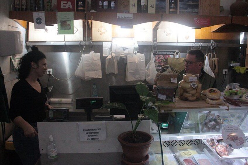 A bakery counter with a woman standing, a computer monitor, and various baked goods on display. 2
