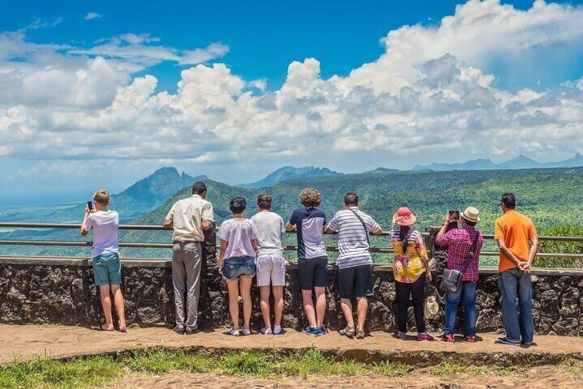 A group of people standing on a stone platform overlooking a mountainous landscape. 2