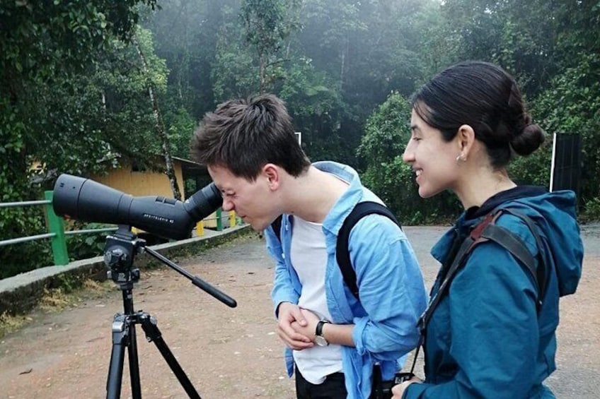 Two people observing through a telescope in a forested area. 2