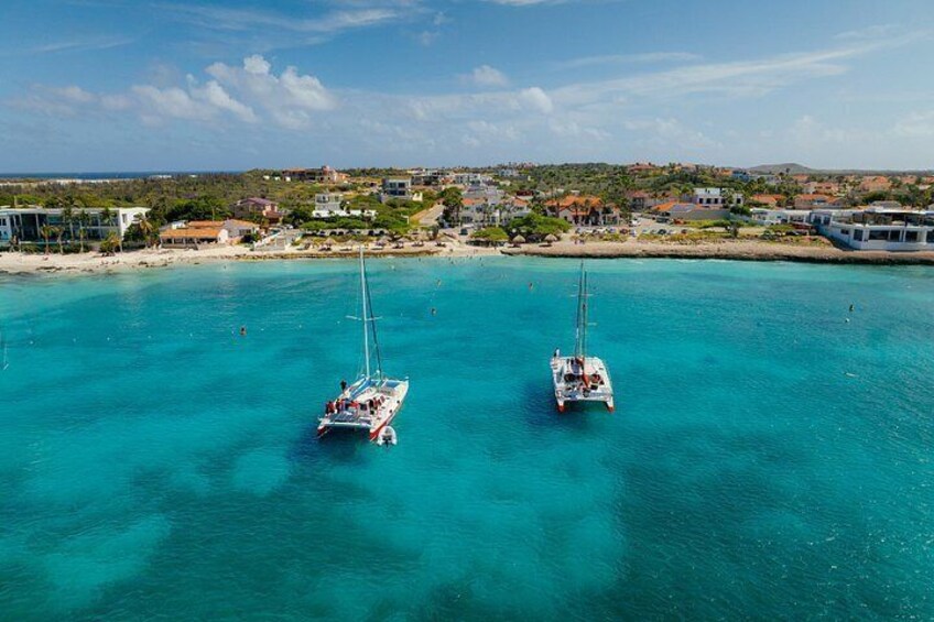Two sailboats on turquoise water with a coastal town in the background. 4