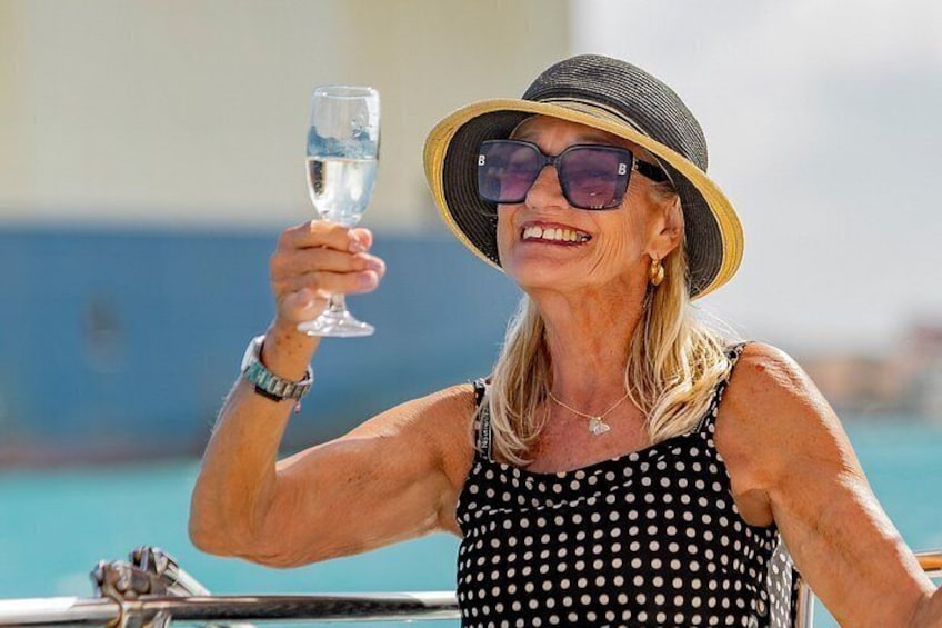 A person holding a glass of water, wearing a polka dot dress and a wide-brimmed hat, with a body of water and a clear sky in the background. 3