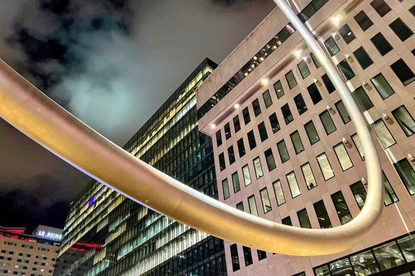 A nighttime cityscape with illuminated buildings and a prominent curved structure. 3