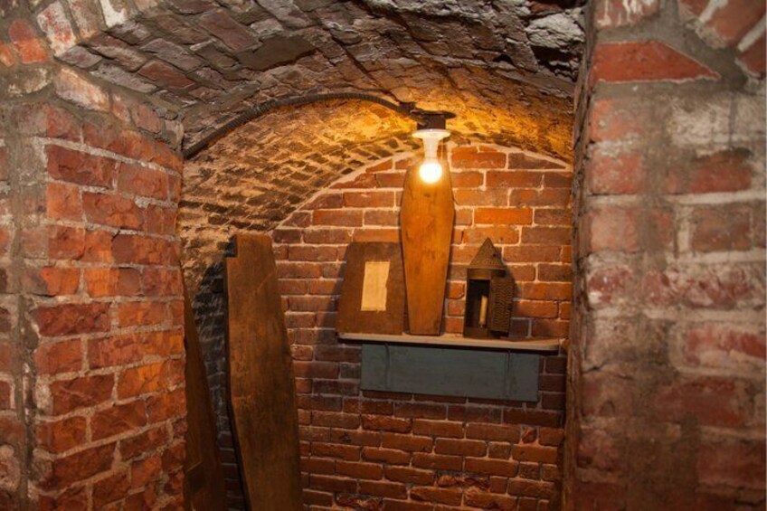 A brick-walled room with a hanging light fixture and wooden objects. 4