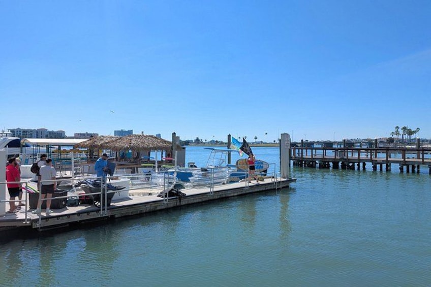 A marina with boats docked, a pier extending into the water, and a clear blue sky. 2