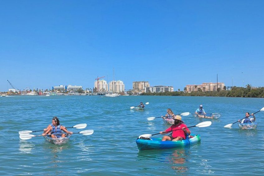 People kayaking on a calm body of water with a city skyline in the background. 4