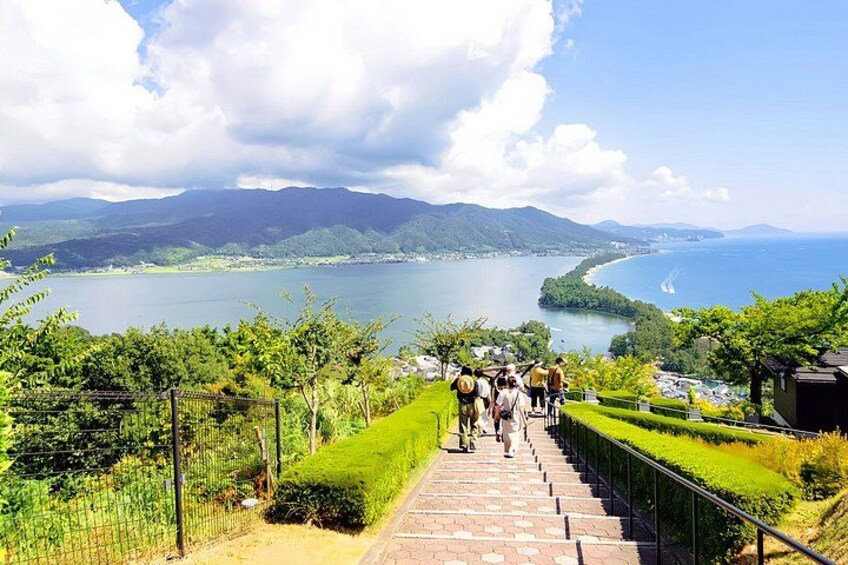 A staircase leading to a scenic overlook with a lake and mountains in the background. 3