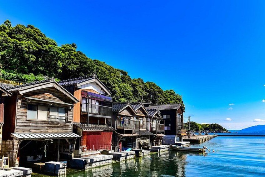 Traditional wooden houses by a calm lake with a forested hill in the background. 5