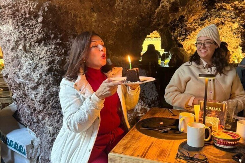Two people dining in a cave-like restaurant with a candle on the table. 2