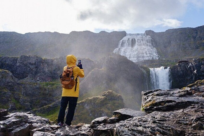Eine Person in einer gelben Jacke fotografiert einen Wasserfall. 3