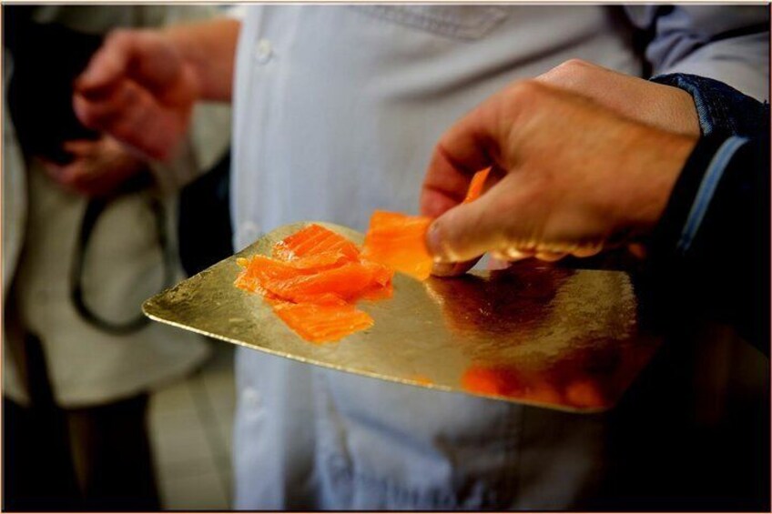 A person holding a knife with salmon slices on it. 3