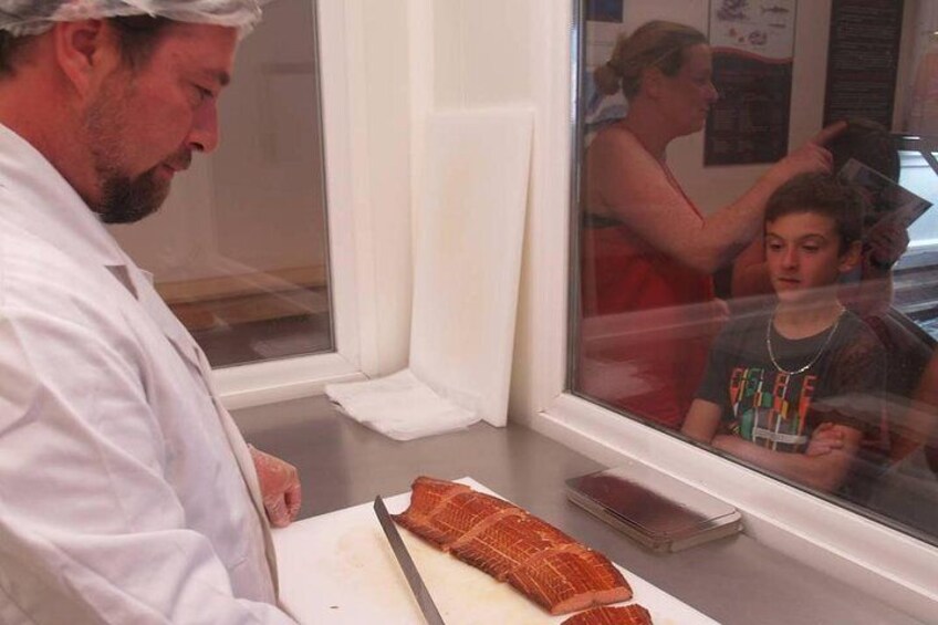 A person cutting food in a kitchen with a window and a reflection of a person. 5