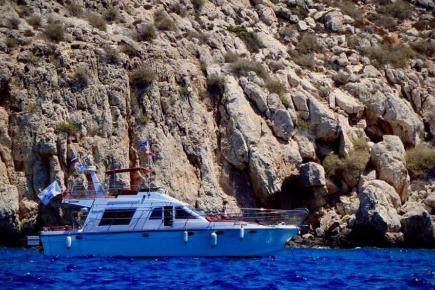 A boat on a body of water with rocky cliffs in the background. 1
