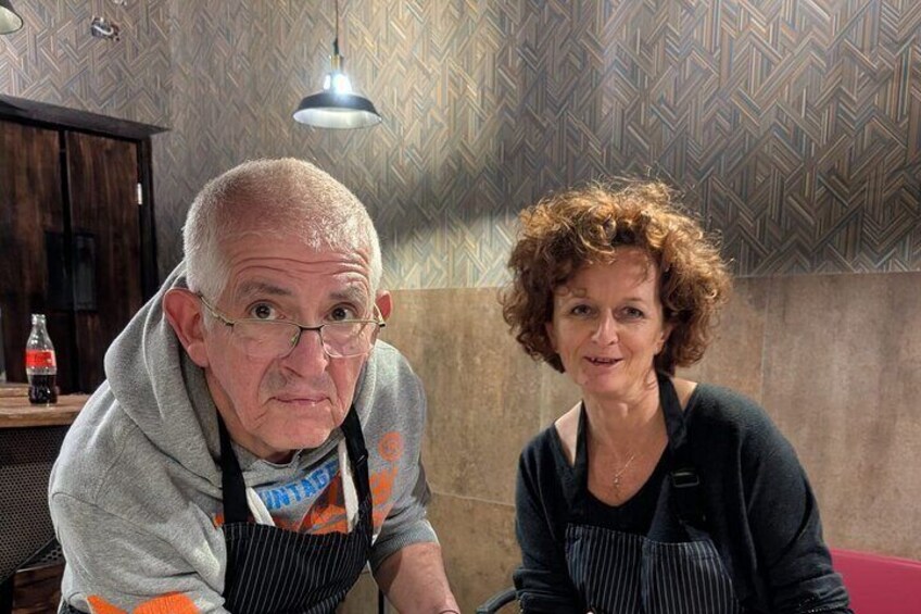 Dos personas en una cocina con papel tapiz estampado y una lámpara colgante. 2