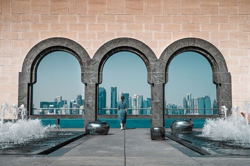 A person standing between three arches overlooking a city skyline. 1