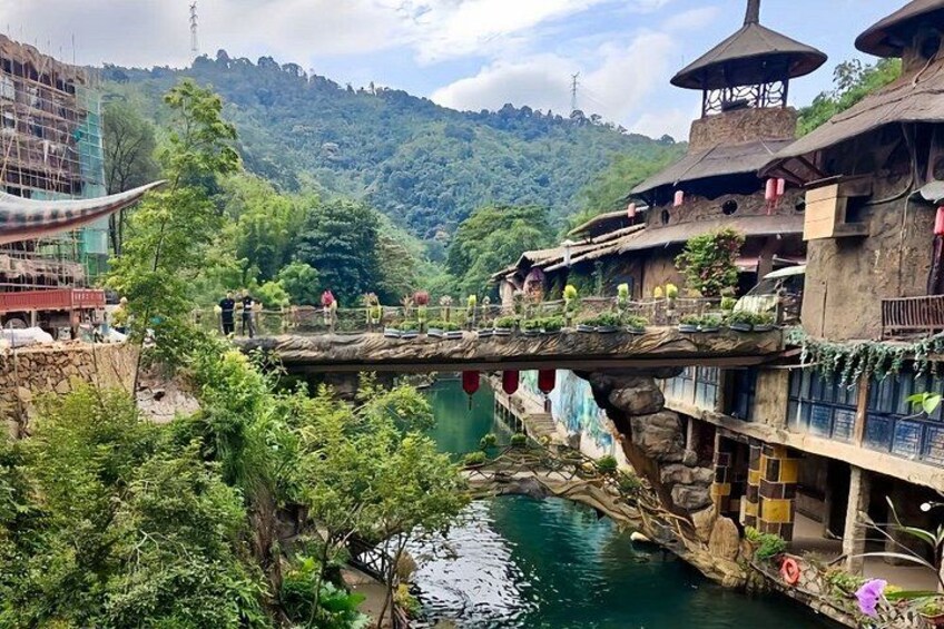 A river with a stone bridge, traditional buildings, and lush greenery. 2