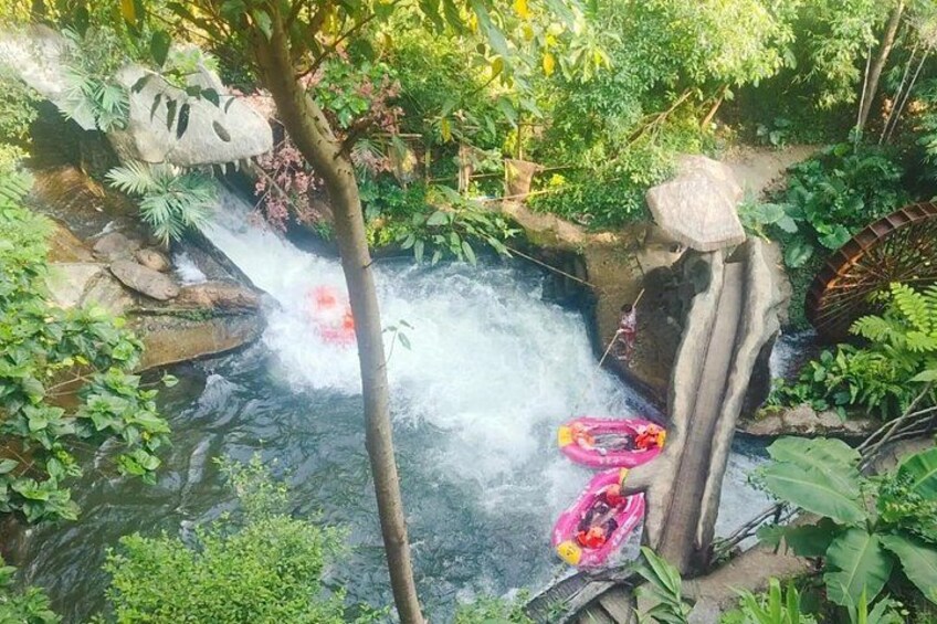 A waterfall in a lush garden with a pink inflatable ring and a red inflatable ring. 3
