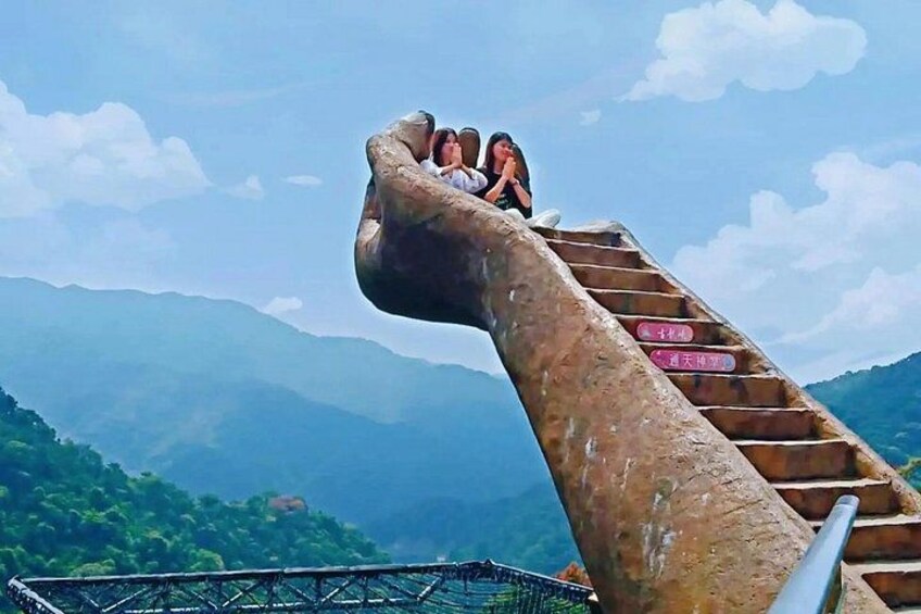A staircase with a unique hand-shaped design, leading to a viewpoint with a mountainous landscape in the background. 5