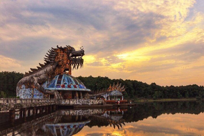 A dragon statue and a temple by a lake at sunset. 2