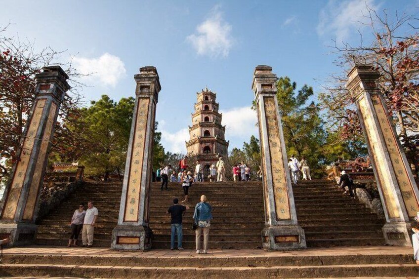 A temple complex with a multi-tiered pagoda, stone staircases, and visitors ascending. 1