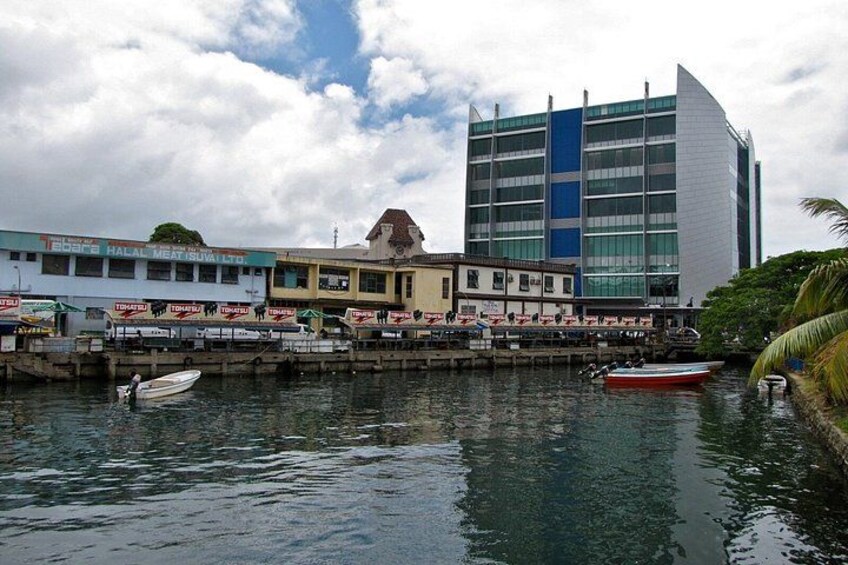 A waterfront with boats, a building with a blue and white facade, and a smaller building with a yellow facade. 2